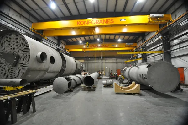 20-ton Konecranes overhead cranes spanning the Axton fabrication bay with stainless vessels and tubesheets staged below