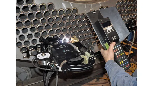 AMI orbital welding head running a tube-to-tubesheet weld with handheld pendant control